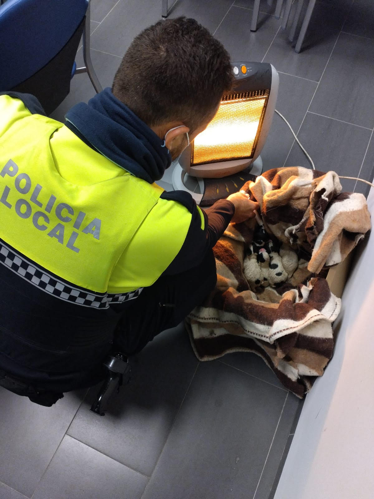 Un policía local junto a los cachorros de perro rescatados.